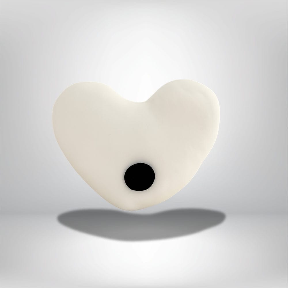 Coussin décoratif en forme de cœur blanc avec un motif noir, posé sur un fond neutre élégant