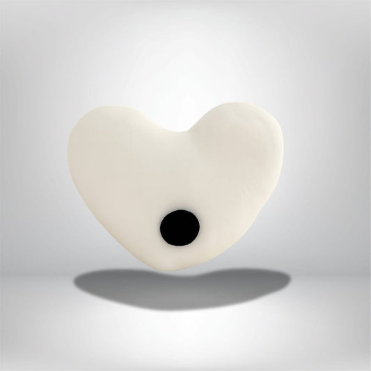 Coussin décoratif en forme de cœur blanc avec un motif noir, posé sur un fond neutre élégant