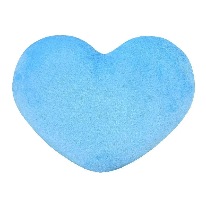 Coussin en forme de cœur, doux et bleu, posé sur un canapé, ajoutant une touche déco chaleureuse