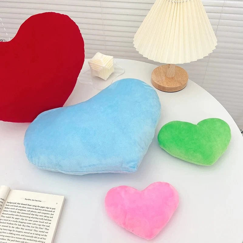 Coussins en forme de cœur, en velours doux, colorés en bleu, rouge, vert et rose, sur une table moderne