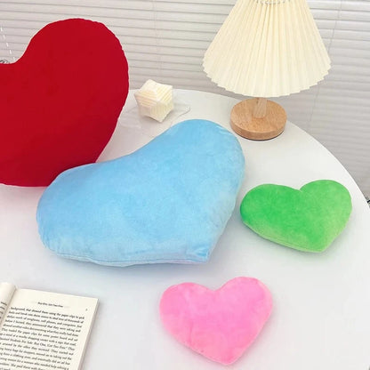 Coussins en forme de cœur, en velours doux, colorés en bleu, rouge, vert et rose, sur une table moderne