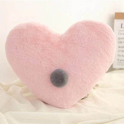 Coussin décoratif en forme de cœur rose, doux au toucher, posé sur un tissu léger dans un salon