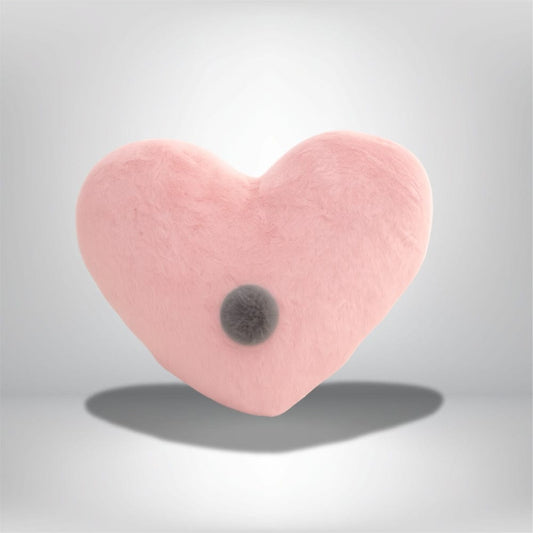 Coussin décoratif en forme de cœur rose avec une texture douce, posé sur un fond neutre