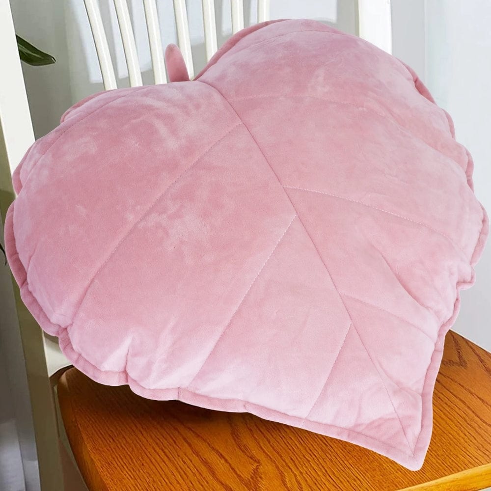 Coussin cœur en velours rose, posé sur une table en bois, ajoutant une touche décorative à l'intérieur