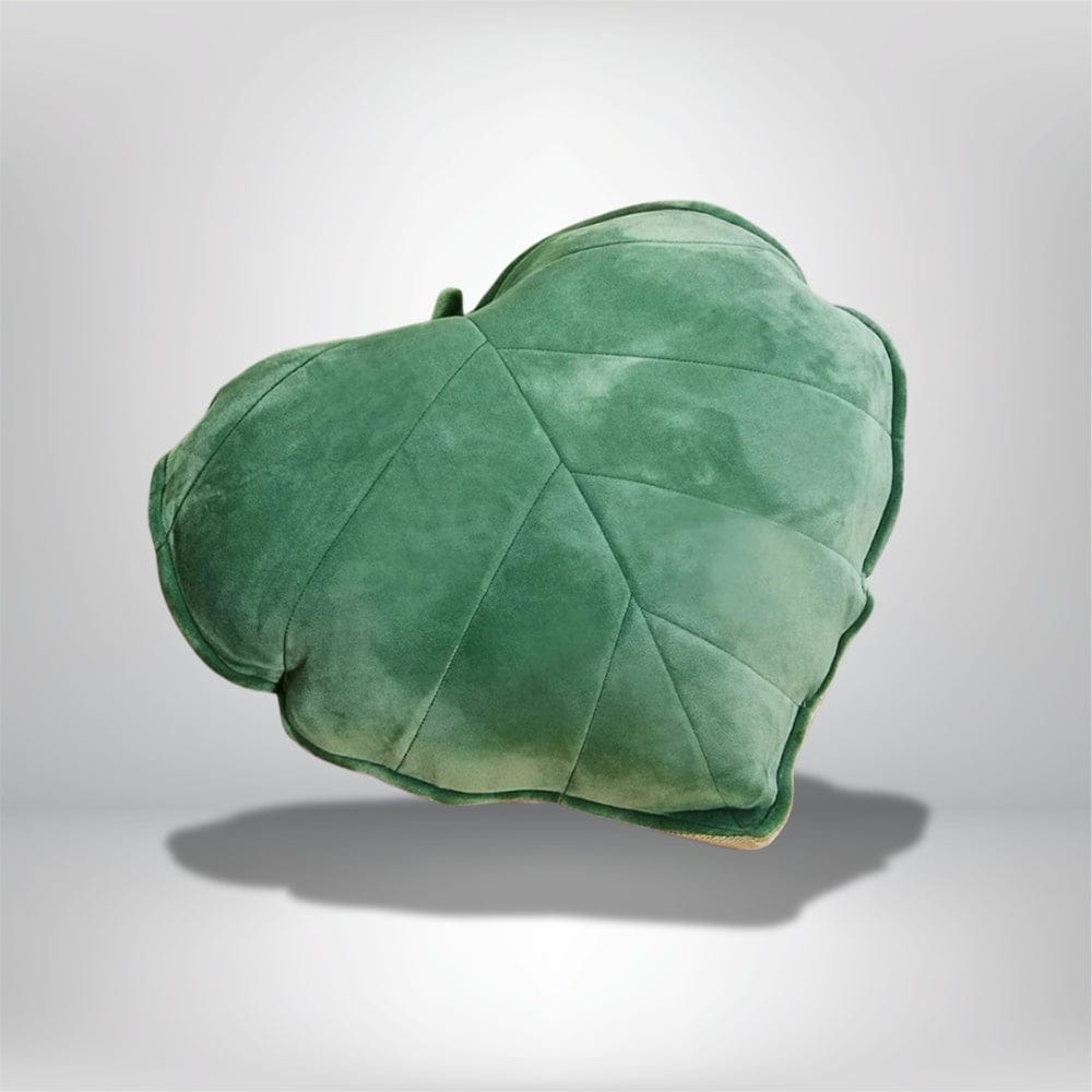 Coussin décoratif en velours vert en forme de feuille, posé sur un fond neutre, idéal pour le canapé