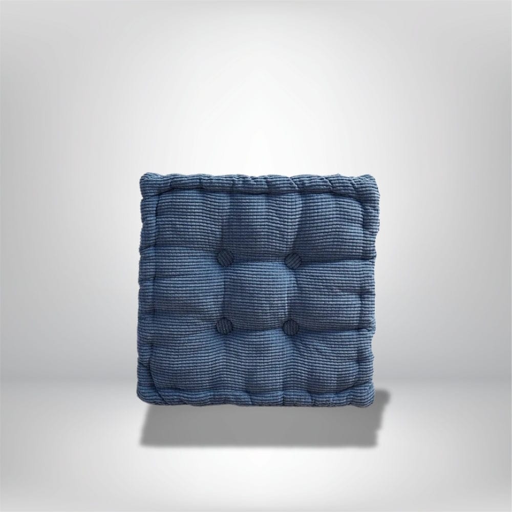 Coussin d'assise bleu en tissu côtelé, avec des boutons décoratifs, posé sur un fond neutre