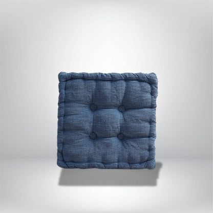Coussin d'assise bleu en tissu côtelé, avec des boutons décoratifs, posé sur un fond neutre