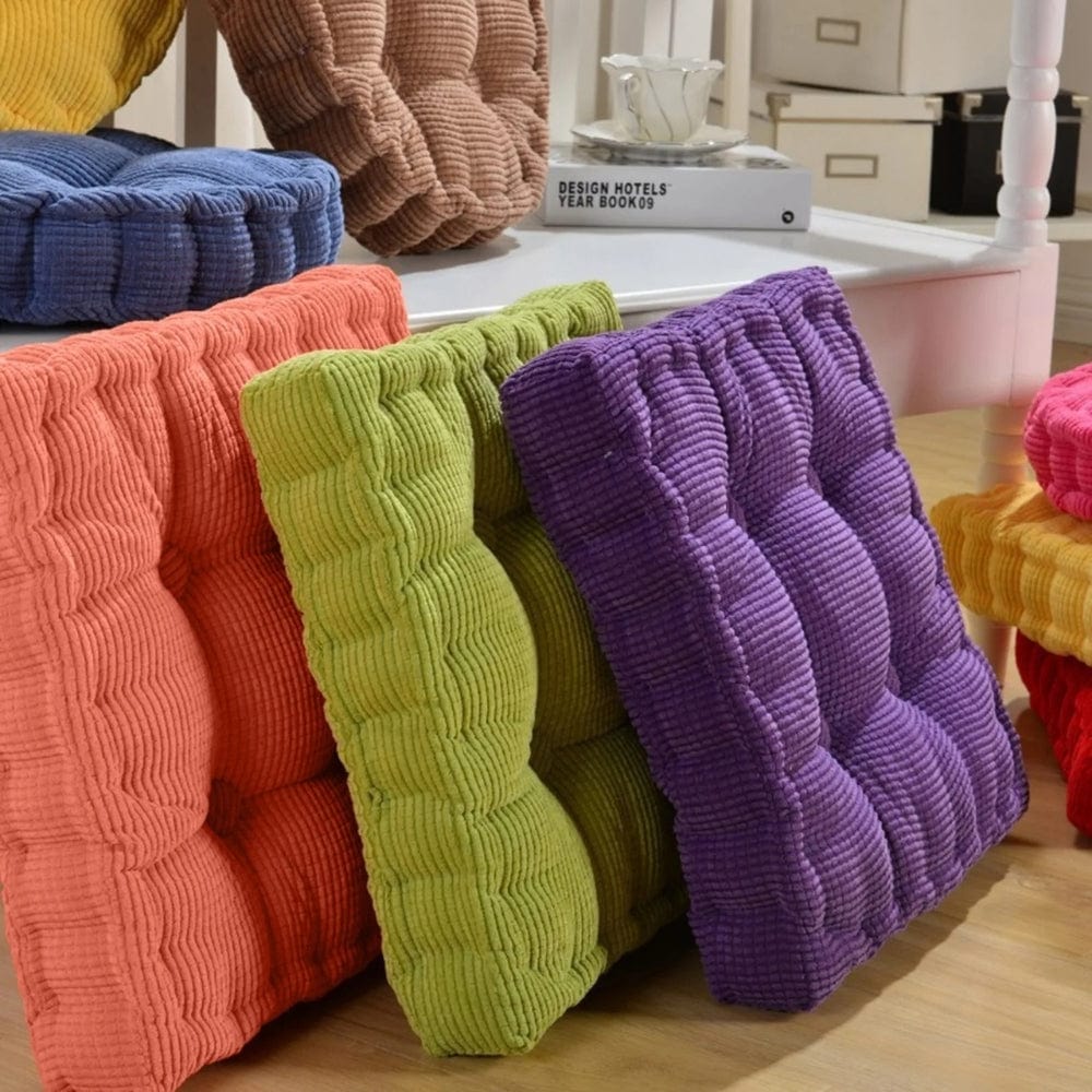 Coussins d'assise colorés en velours côtelé, disposés sur une surface en bois, ajoutant une touche décorative à un intérieur