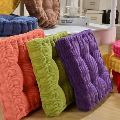 Coussins d'assise colorés en velours côtelé, disposés sur une surface en bois, ajoutant une touche décorative à un intérieur