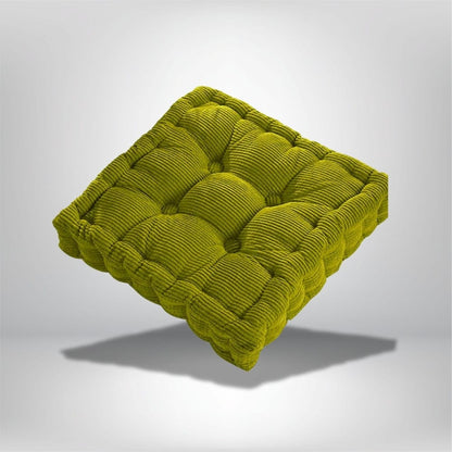 Coussin de chaise en velours côtelé vert, avec un motif matelassé, posé sur un fond neutre