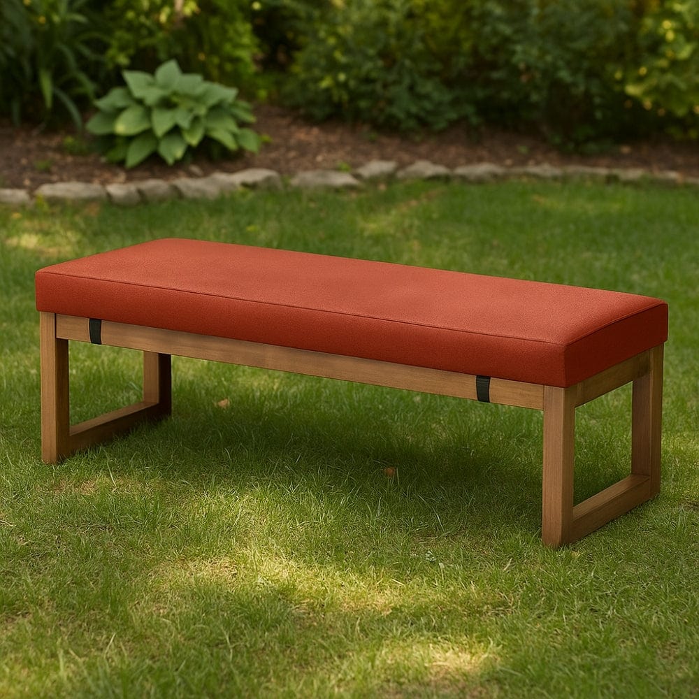 Coussin décoratif orange sur une banquette en bois, posé sur une pelouse verte, parfait pour l'extérieur