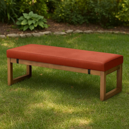 Coussin décoratif orange sur une banquette en bois, posé sur une pelouse verte, parfait pour l'extérieur