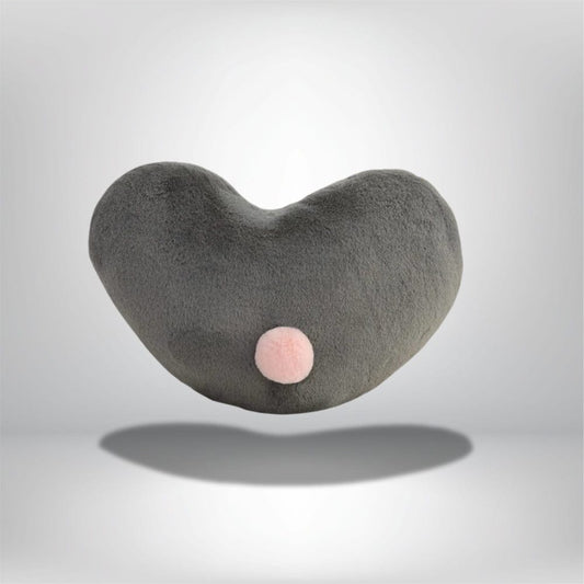 Coussin décoratif en forme de cœur gris avec un pompon rose, idéal pour un canapé moderne
