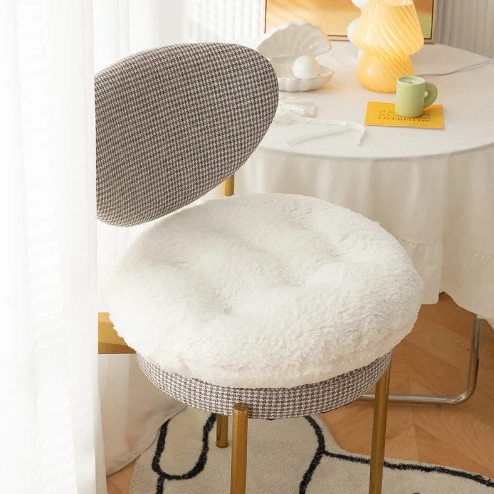 Coussin de chaise rond en fausse fourrure blanche sur une chaise à motifs gris dans un intérieur moderne