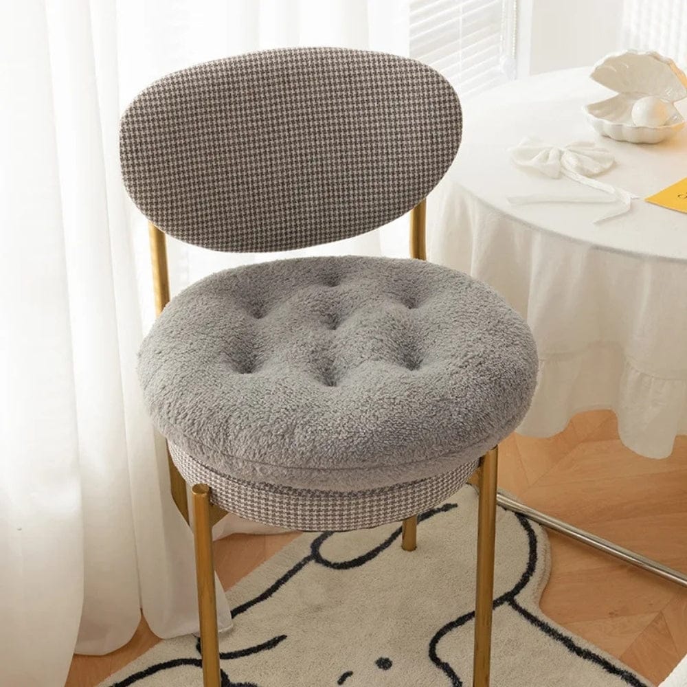 Coussin de chaise rond en tissu gris doux, avec un motif à carreaux sur la structure dorée de la chaise
