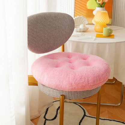 Coussin de chaise rond en tissu rose doux, posé sur une chaise à motifs gris et dorés dans un salon