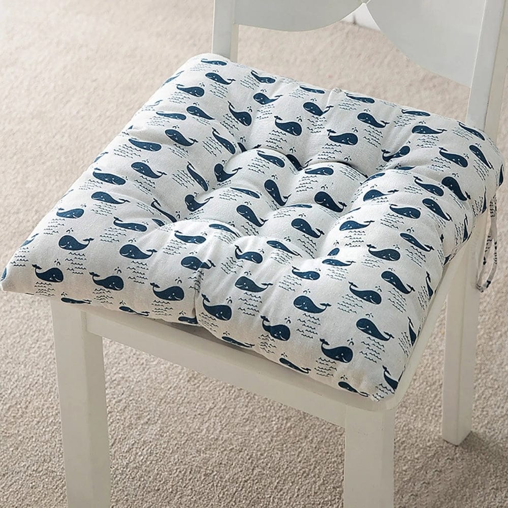 Coussin de chaise de jardin avec motif de baleines bleues sur fond beige, placé sur une chaise blanche