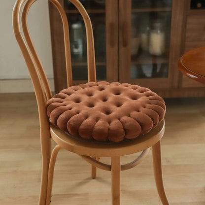 Coussin de chaise rond en velours marron, avec un design capitonné, posé sur une chaise en bois dans un salon