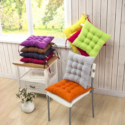 Coussins de chaise épais aux couleurs vives, orange, gris, violet et vert, disposés sur une chaise dans un salon lumineux