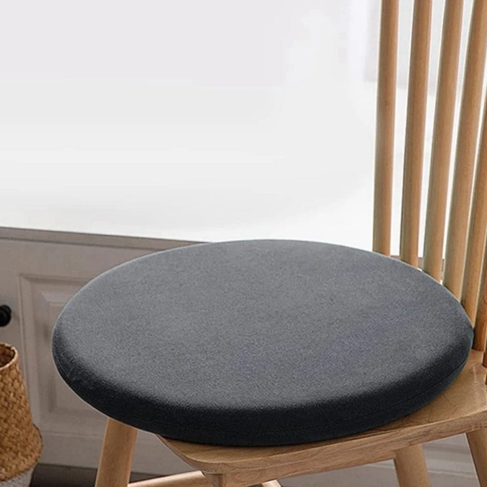 Coussin de chaise ergonomique rond en tissu gris posé sur une chaise en bois dans un intérieur moderne