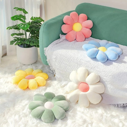Coussins décoratifs en forme de fleurs aux couleurs pastel, posés sur un canapé vert dans un salon lumineux