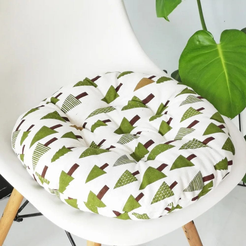 Coussin de chaise rond avec motifs d'arbres verts sur fond blanc, posé sur une chaise moderne en plastique