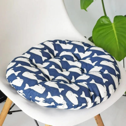 Coussin de chaise rond bleu marine avec motifs de baleines blanches, posé sur une chaise moderne