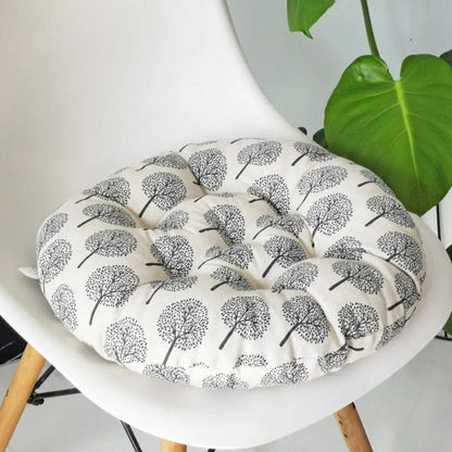 Coussin de chaise rond en tissu beige avec motifs d'arbres noirs, posé sur une chaise moderne