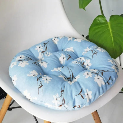 Coussin de chaise rond en tissu bleu clair avec des motifs floraux blancs et des touches de brun