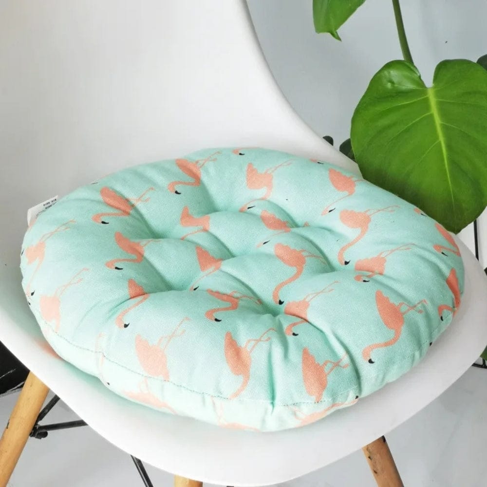 Coussin de chaise rond en tissu mint avec motifs de flamants roses, posé sur une chaise moderne