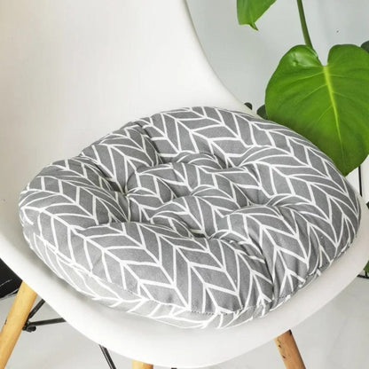 Coussin de chaise rond en tissu gris avec motif géométrique blanc, posé sur une chaise moderne