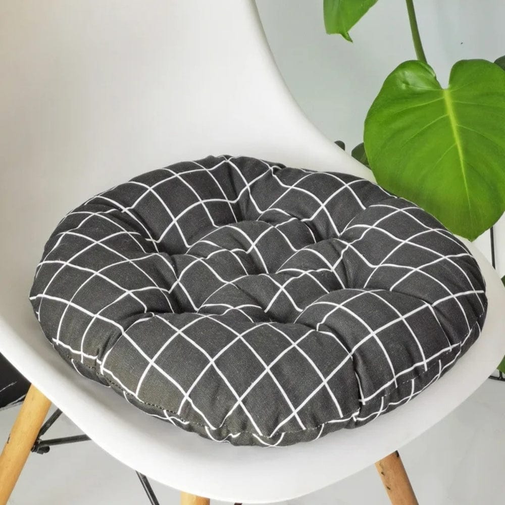 Coussin de chaise rond en tissu noir à motifs carrés blancs, posé sur une chaise moderne