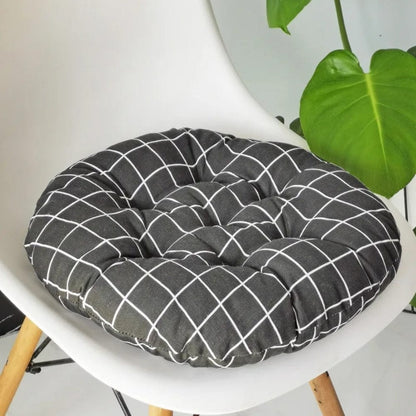 Coussin de chaise rond en tissu noir à motifs carrés blancs, posé sur une chaise moderne