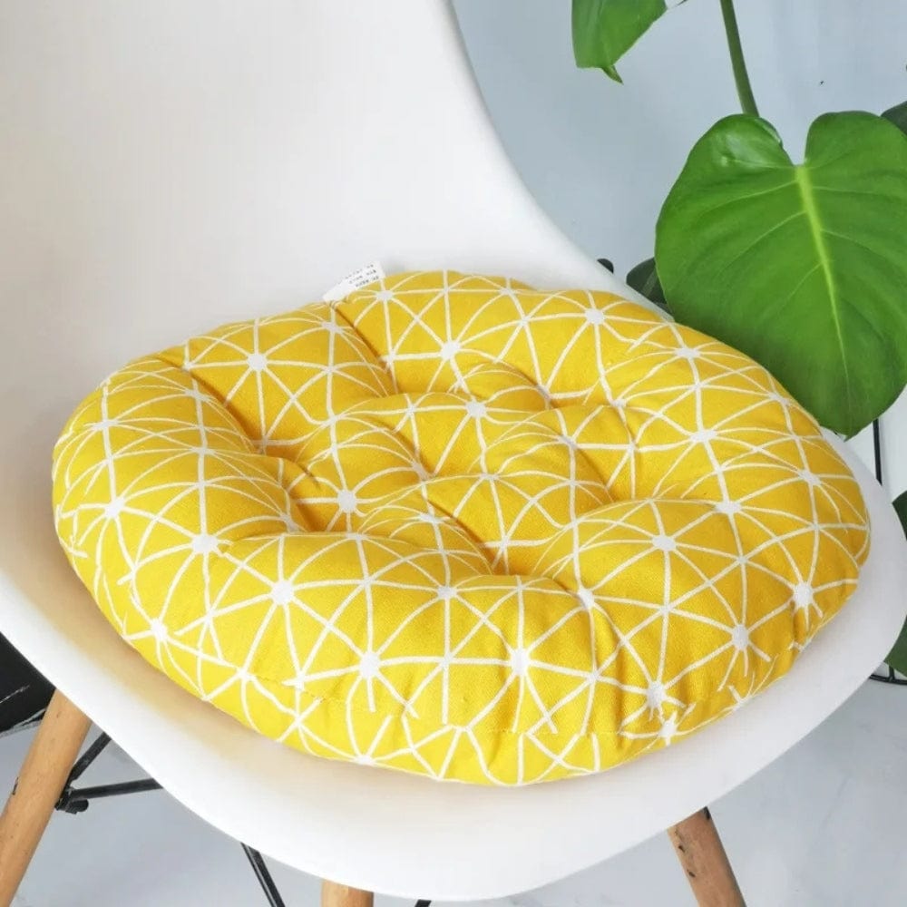 Coussin de chaise rond jaune avec motif géométrique blanc, posé sur une chaise moderne au design épuré
