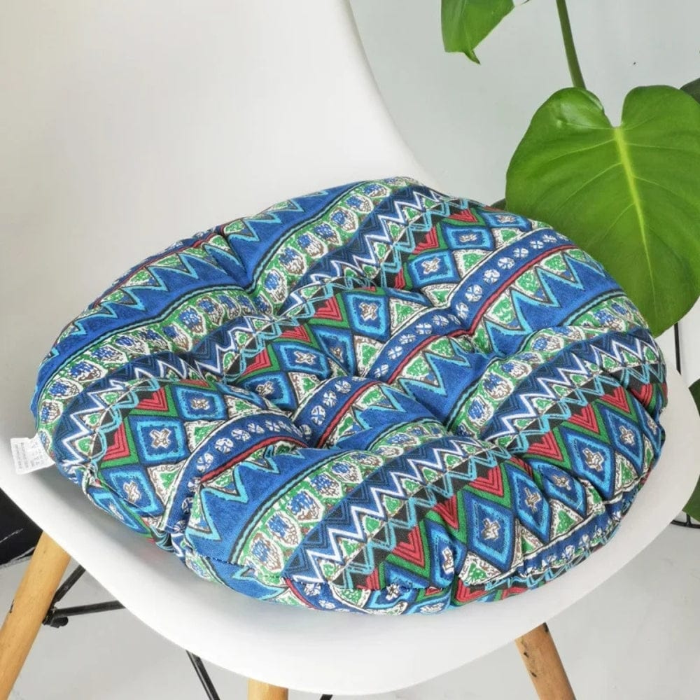Coussin de chaise rond aux motifs géométriques bleus, verts et rouges, posé sur une chaise en bois
