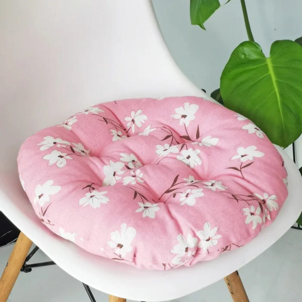 Coussin de chaise rond en tissu rose avec des motifs floraux blancs, posé sur une chaise moderne