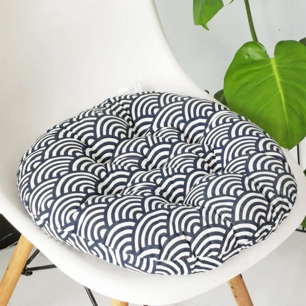 Coussin de chaise rond avec un motif en vagues bleues et blanches, posé sur une chaise moderne