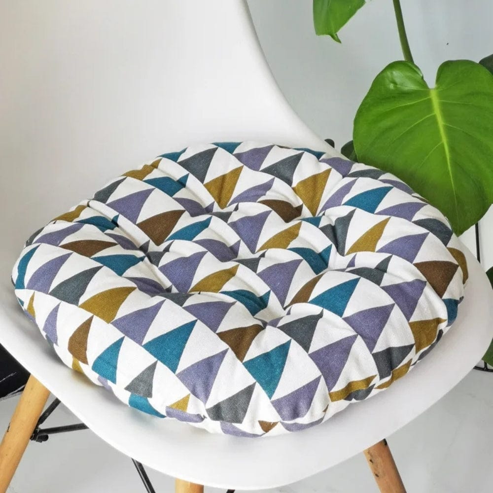Coussin de chaise rond avec motifs géométriques colorés sur fond blanc, posé sur une chaise moderne