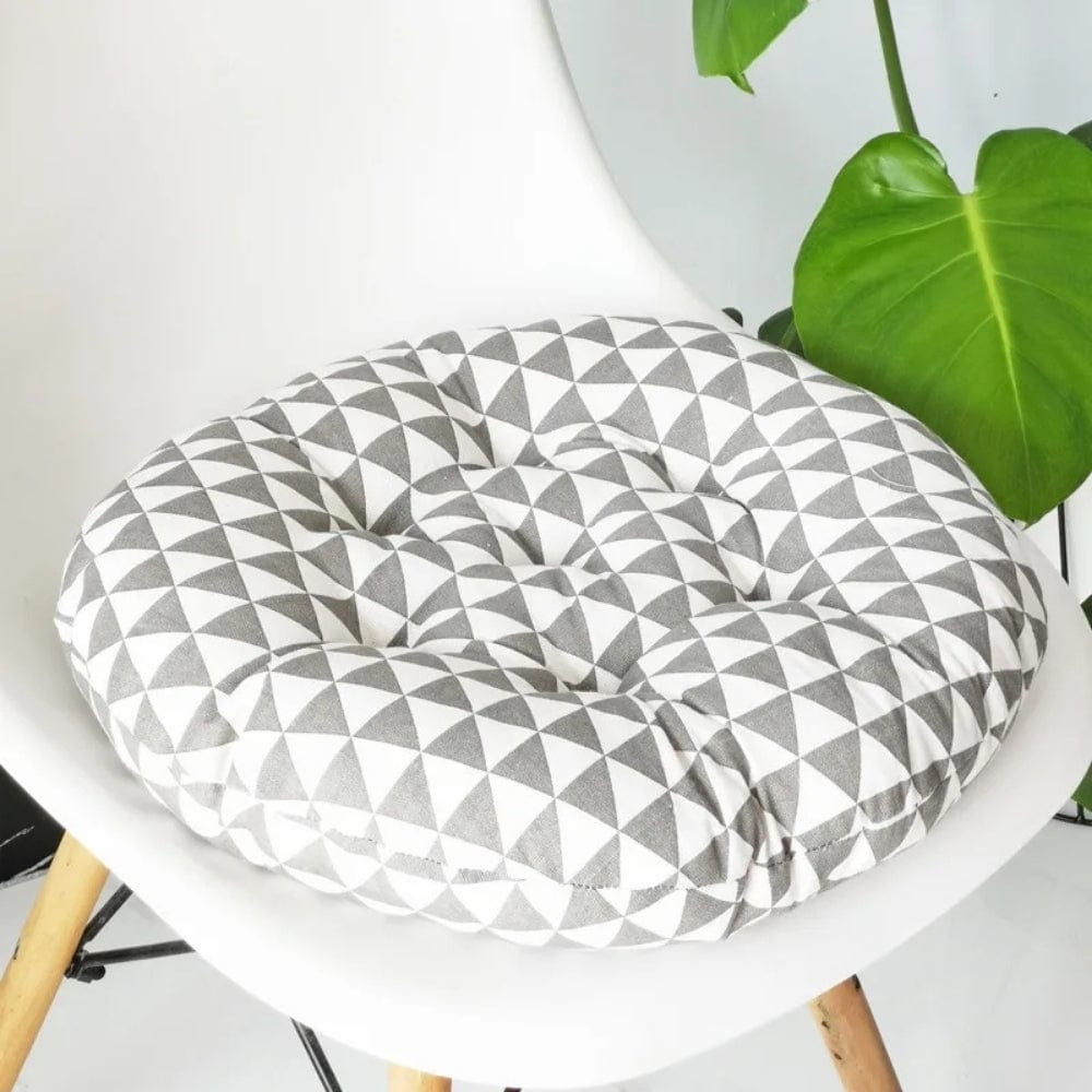 Coussin de chaise rond en tissu gris et blanc avec un motif géométrique de triangles, posé sur une chaise moderne
