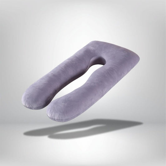 Coussin de grossesse en velours violet, en forme de U, posé sur un fond neutre