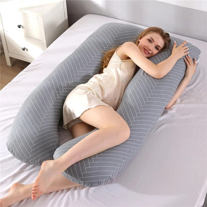 Coussin de grossesse en tissu gris à rayures, posé sur un lit avec une femme allongée