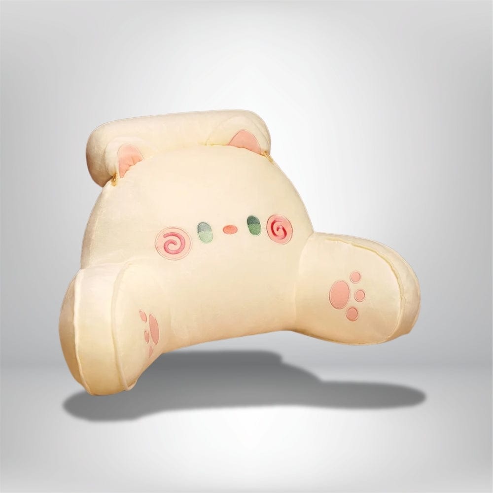 Coussin décoratif en forme de chat, couleur crème avec des motifs roses, posé sur un lit douillet