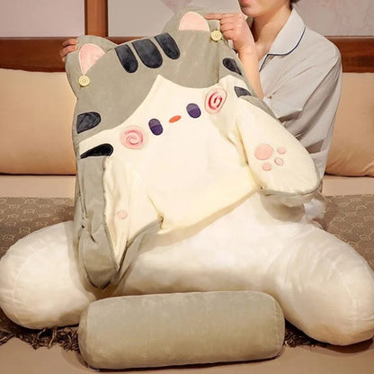 Coussin décoratif en forme de chat, doux, avec des couleurs crème et gris, posé sur un lit