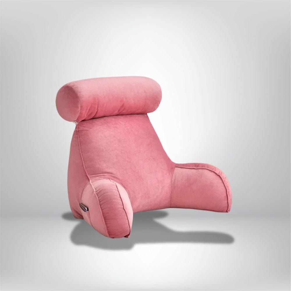 Coussin de lecture en velours rose, avec un dossier haut et des accoudoirs, posé sur un fond neutre