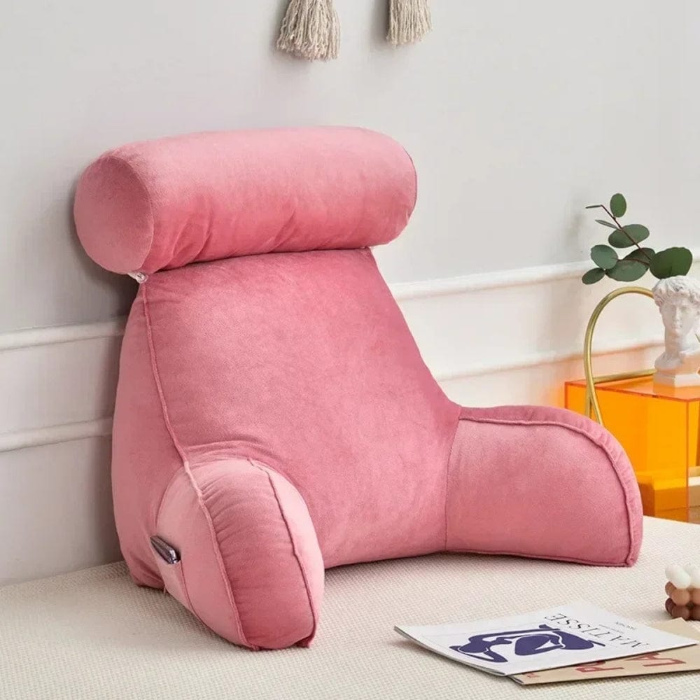 Coussin de lecture en velours rose, avec un appui-tête, posé sur un canapé dans un salon moderne