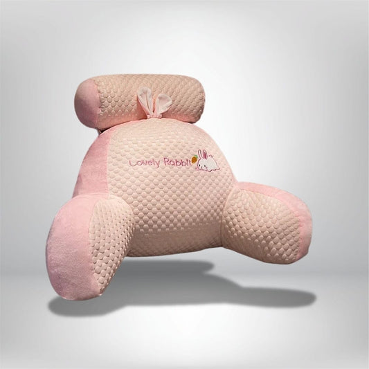 Coussin de lecture en forme de lapin, en velours rose et beige, posé sur un fond neutre