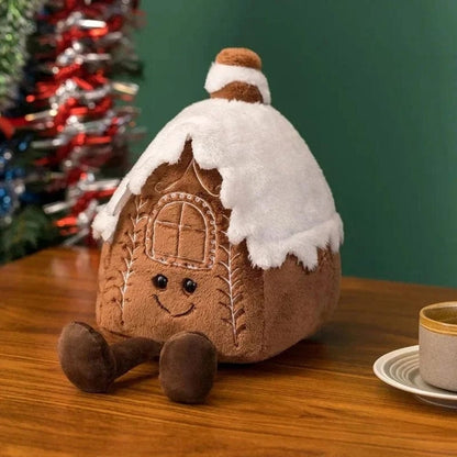 Coussin décoratif en forme de maison en pain d'épice, marron avec un toit en feutre blanc, sur une table en
