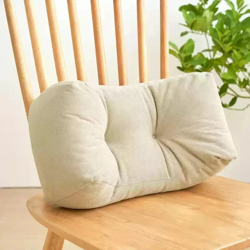 Coussin décoratif beige en tissu texturé, posé sur une chaise en bois, idéal pour une sieste confortable