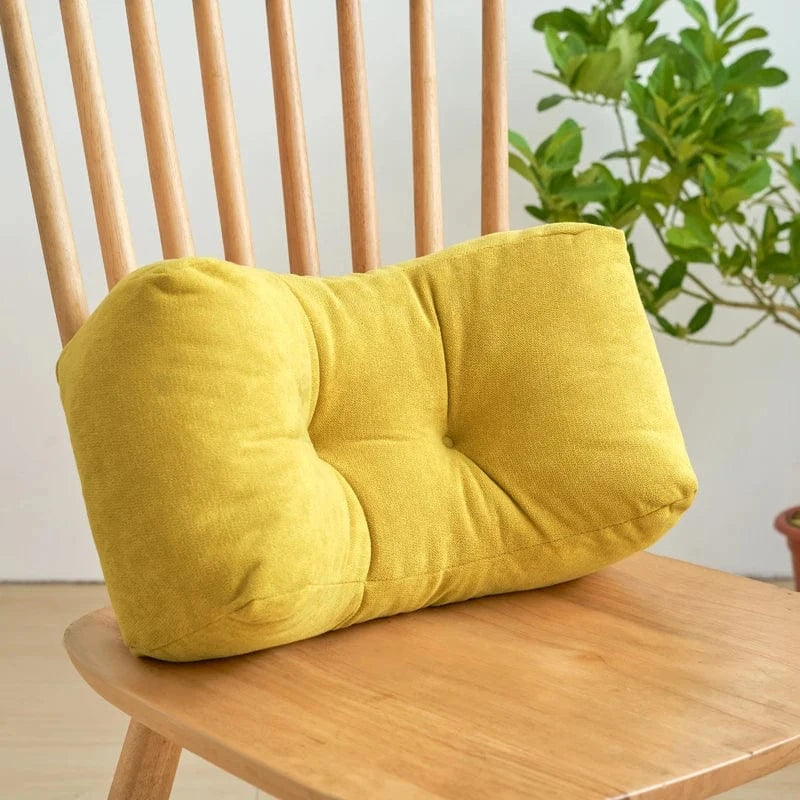 Coussin déco jaune en velours, à forme rectangulaire, posé sur une chaise en bois dans un intérieur lumineux