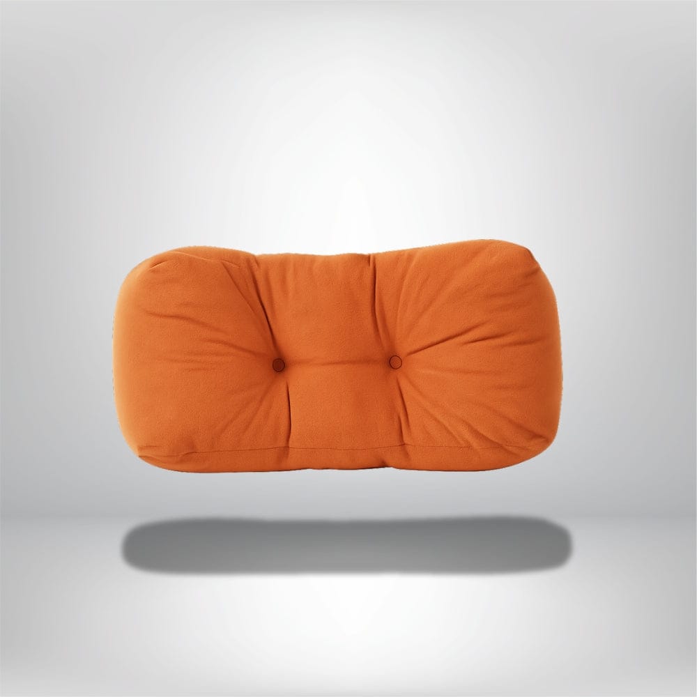 Coussin de sieste orange en velours doux, avec des boutons décoratifs, posé sur un fond neutre